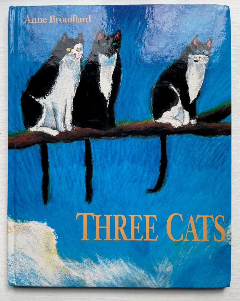 Book cover of 'Three Cats' by Anne Brouillard featuring three stylized cats sitting on a branch against a vibrant blue background.