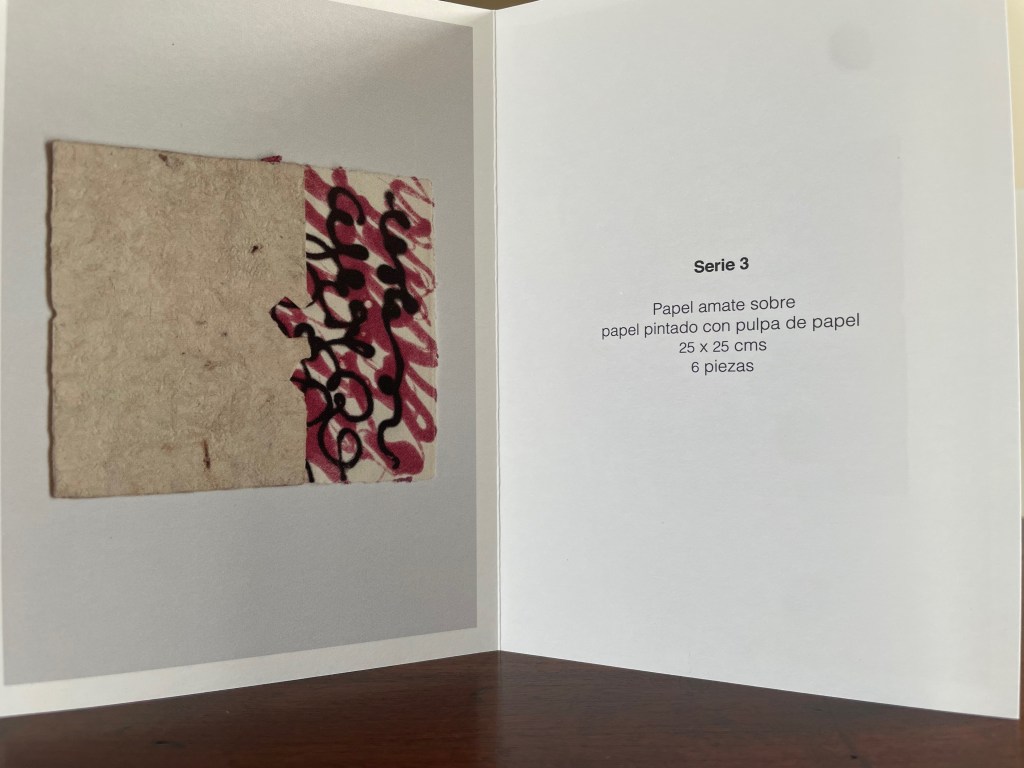 An artistic display of amate paper featuring a painted section with swirling black and pink designs, alongside text describing the artwork's dimensions and details.