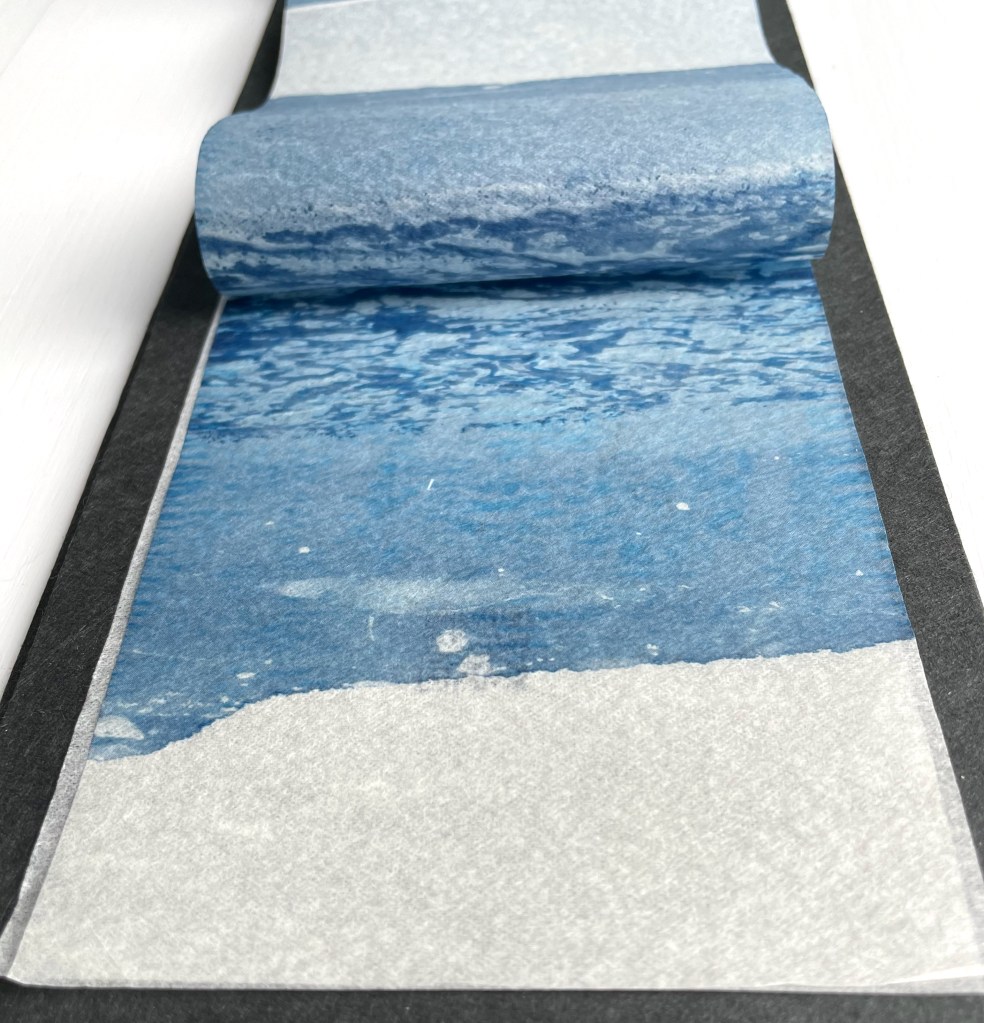 Close-up of a rolled piece of art paper featuring a watercolor-style depiction of ocean waves in shades of blue and white.