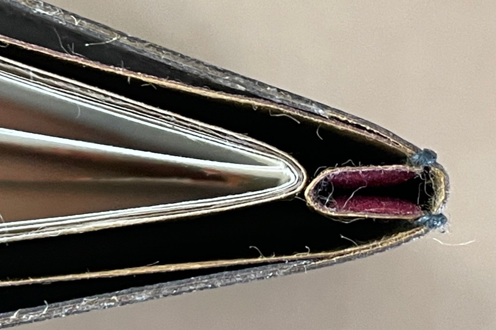 Close-up view of the spine and binding of a unique artist's book titled 'Amorous Embrace', showcasing its stub binding technique and the contrasting colors of the inner pages.