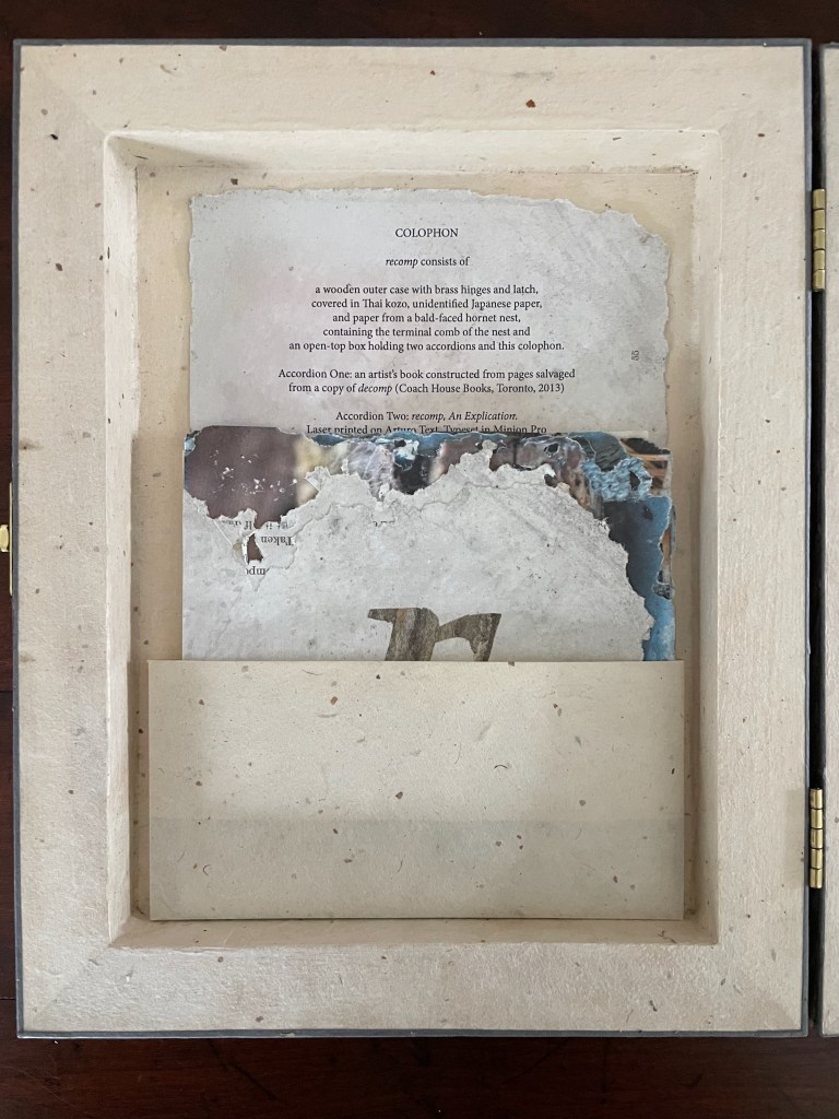 Interior view of an artist's book colophon displaying text on aged paper, framed by a textured outer case made of natural materials.