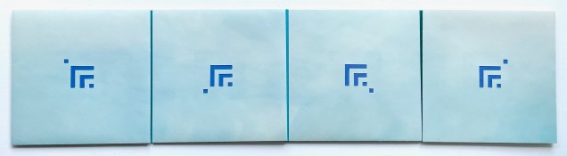 A closed multi-panel book with a light blue cover, featuring a simple blue logo on each panel.