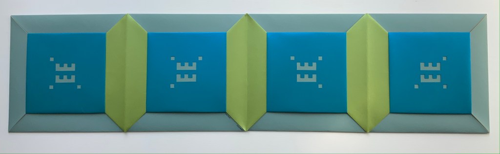 An accordion book structure featuring four brightly colored panels, predominantly blue and green, with geometric patterns and symbols on the panels.