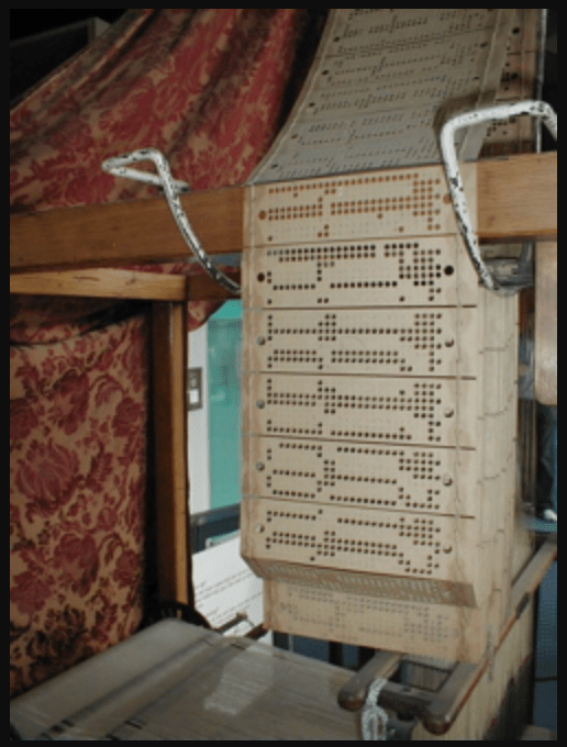 A vintage Jacquard loom with a punched card mechanism, displaying rows of perforations arranged to guide the weaving process.