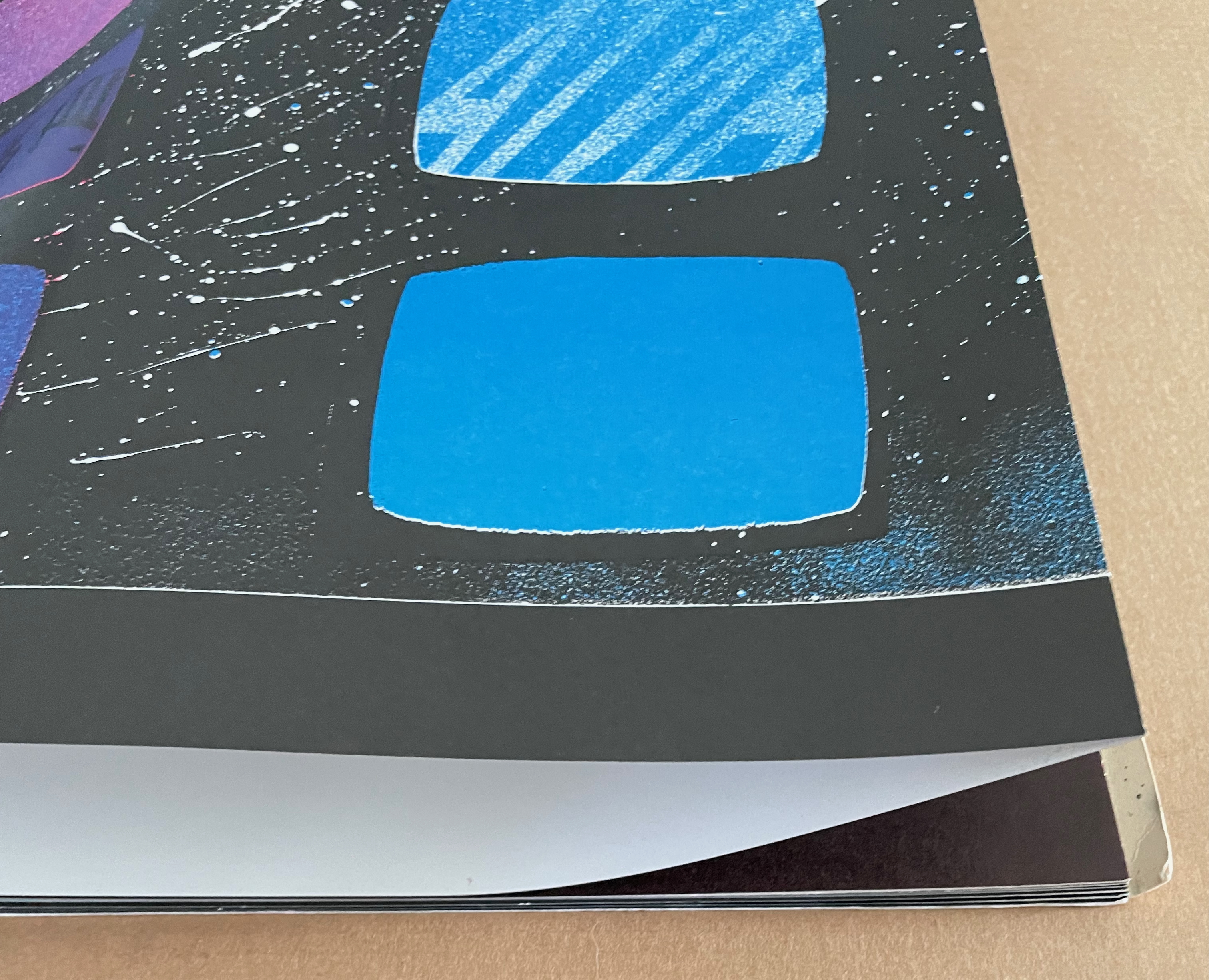 A close-up view of an artistic piece featuring several abstract shapes in bright blue and purple against a dark background with splashes of white.