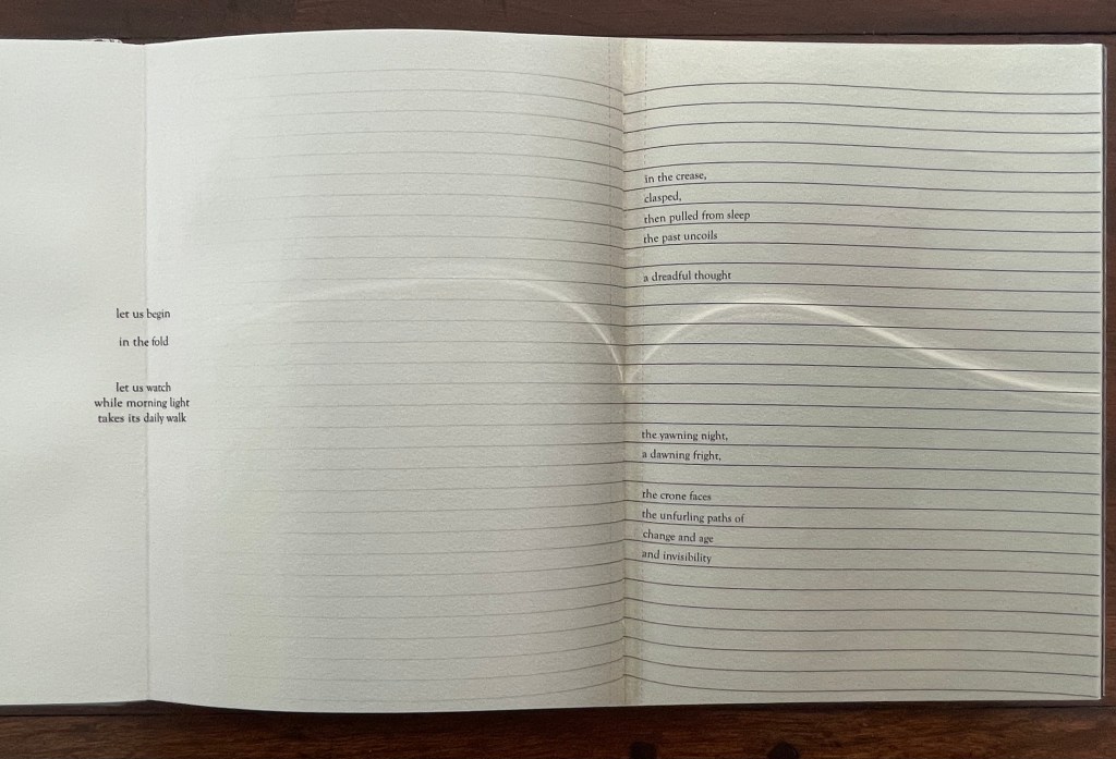 Open pages of a handbound artist's book displaying a poem with lines arranged in a structured format on a lightly textured background.