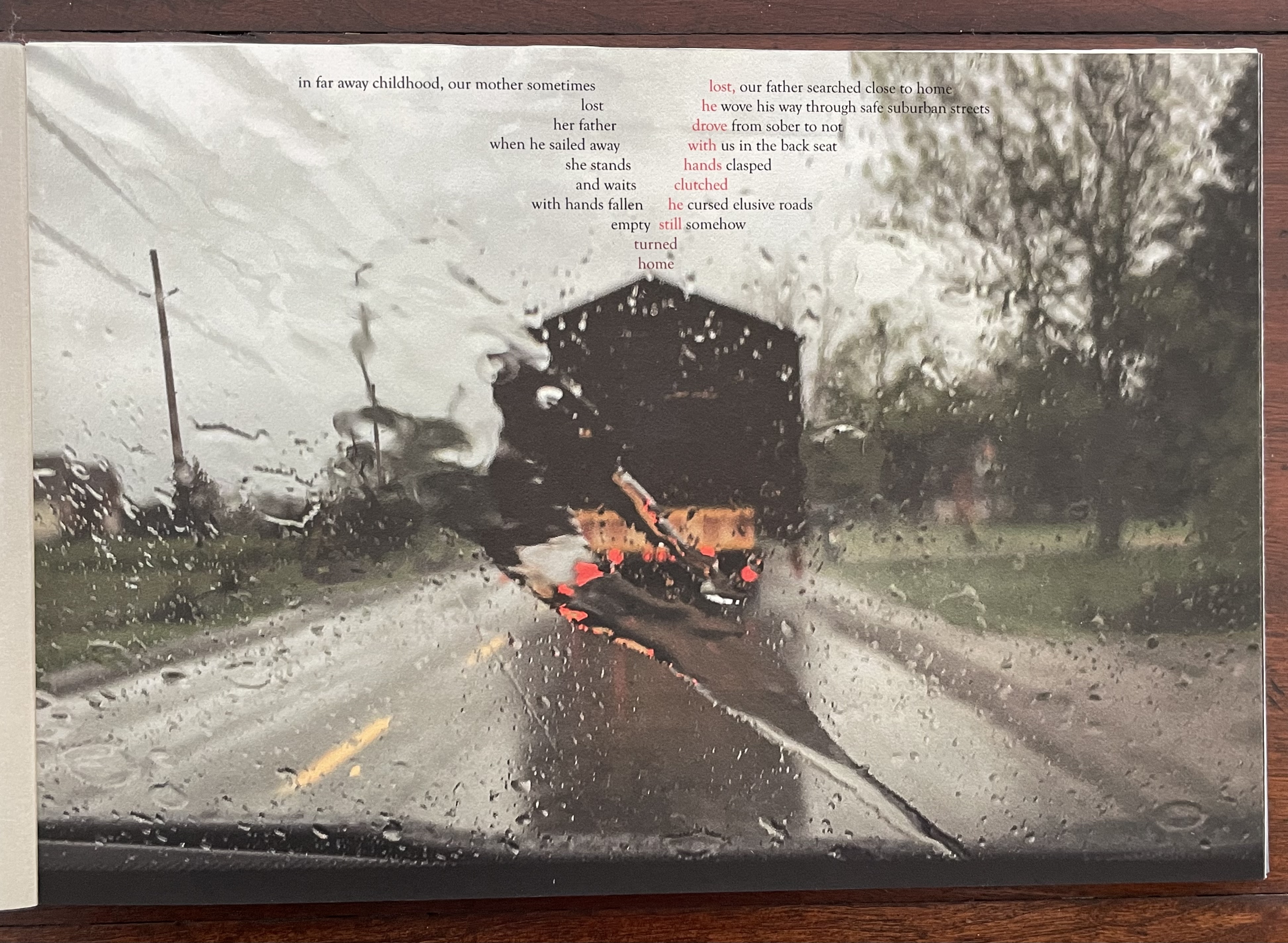 A blurred view of a road seen through a rain-soaked windshield, with streaks of water and a hint of trees and a building in the background. Overlaying the image is a poem reflecting on themes of loss and memory.