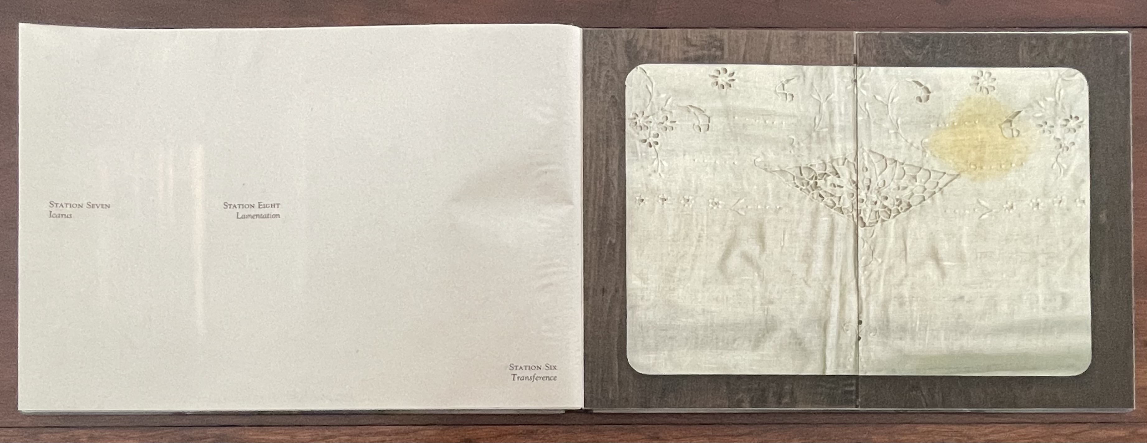 Open artist's book page displaying the titles 'Station Seven: Icarus' and 'Station Eight: Lamentation' alongside an embossed illustration of a bird and floral elements on textured paper.