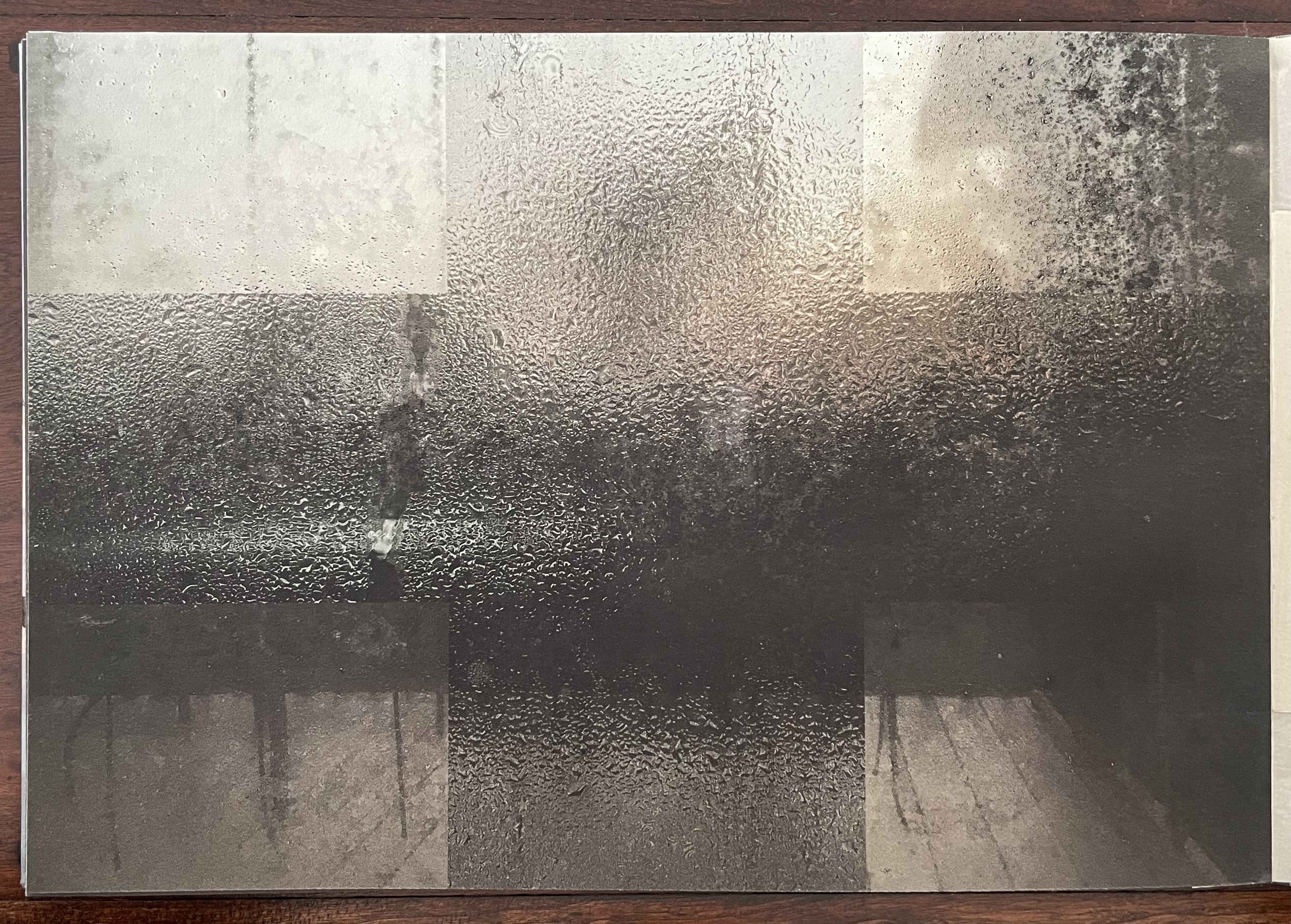 A foggy window pane with water droplets, revealing a blurred view of the exterior and the faint outline of a wooden floor.