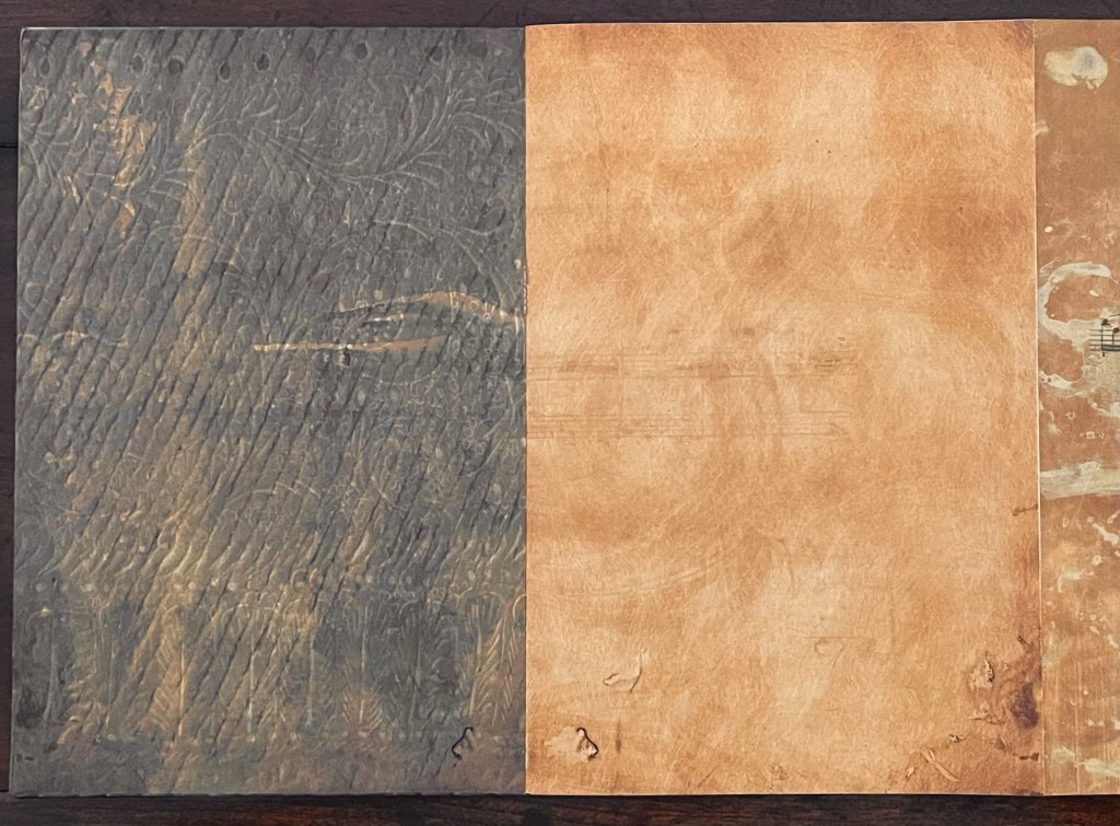 Open artist's book showcasing two pages, one with textured imprint and the other smooth and unmarked, illustrating the intricate design of the book's structure.