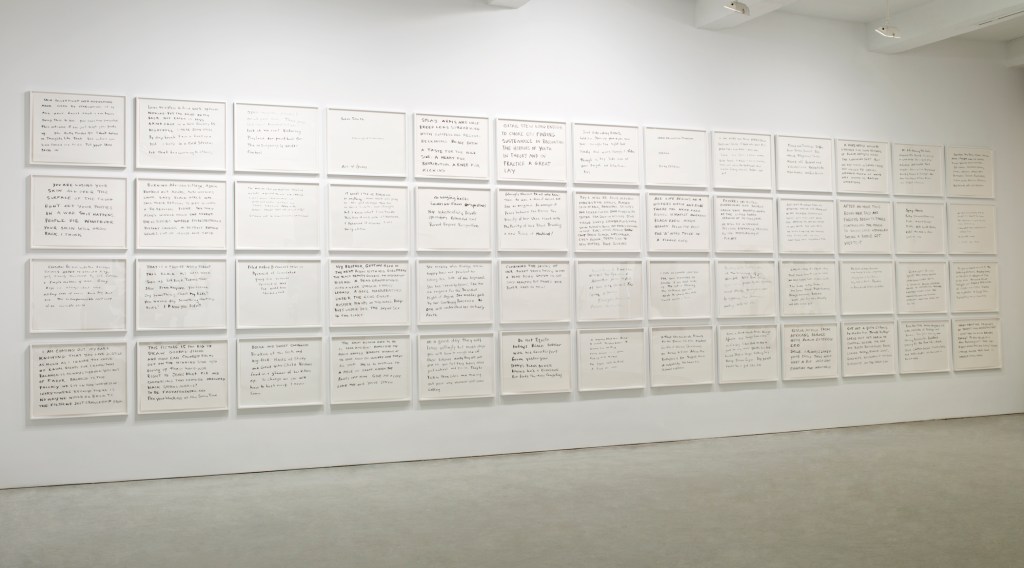 A gallery wall displaying multiple framed sheets of paper with handwritten text, featuring various thoughts and reflections.