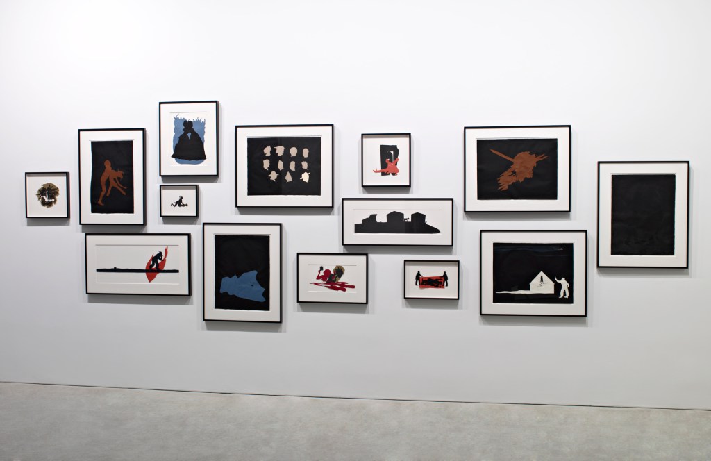 A collection of framed artworks arranged on a white wall, featuring contrasting silhouettes and abstract designs in dark and muted colors.