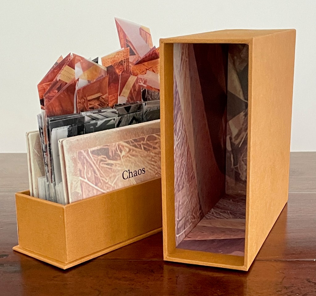 An orange box containing photographs and artwork organized inside, with one visible cover labeled 'Chaos'.