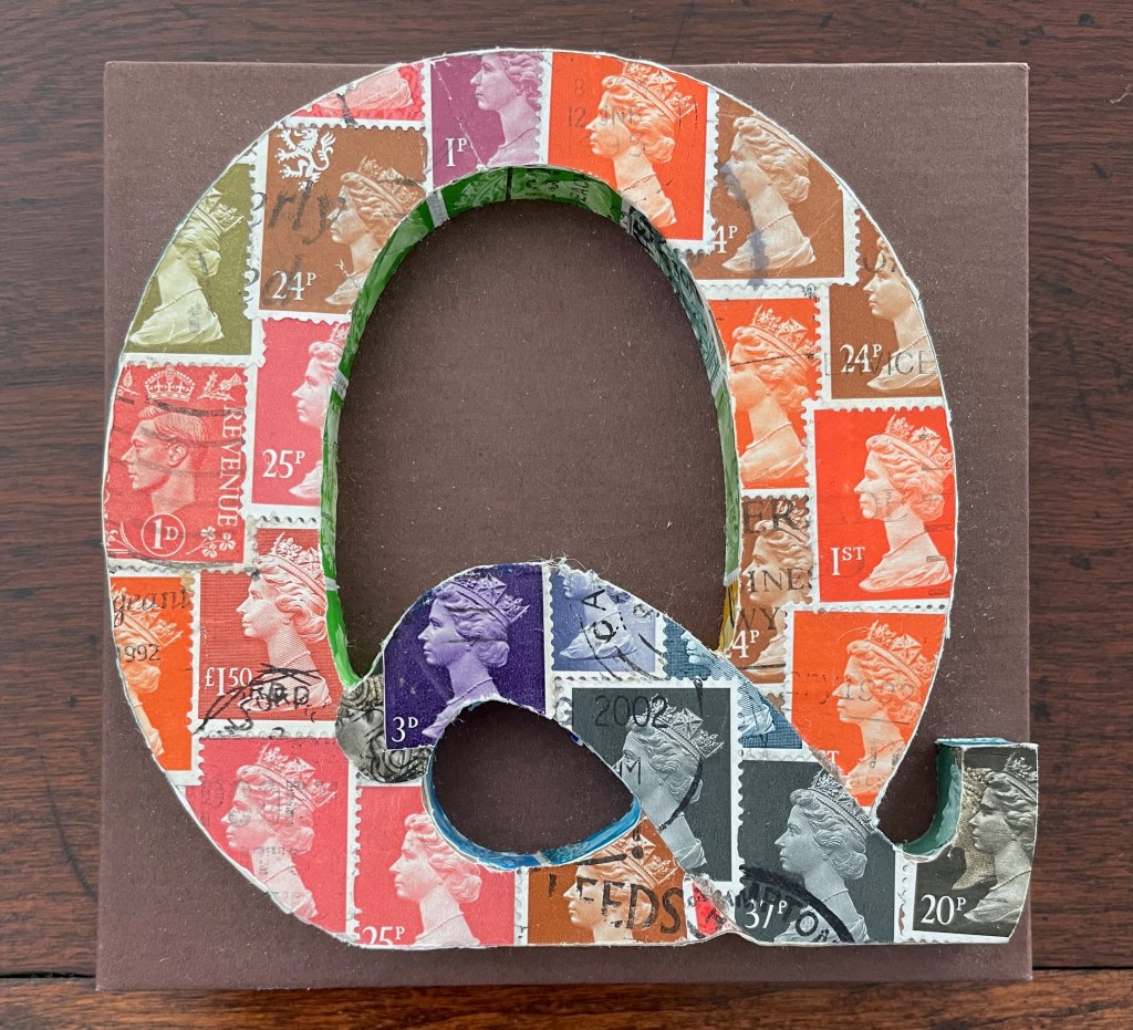 A decorative letter 'Q' made of various colorful postage stamps, showcasing images of royalty and differing denominations against a brown background.