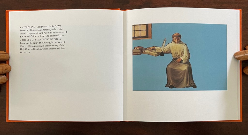 An open page from a book featuring a painting of St. Anthony of Padua in a monastery setting, with text in Italian and English describing his life.
