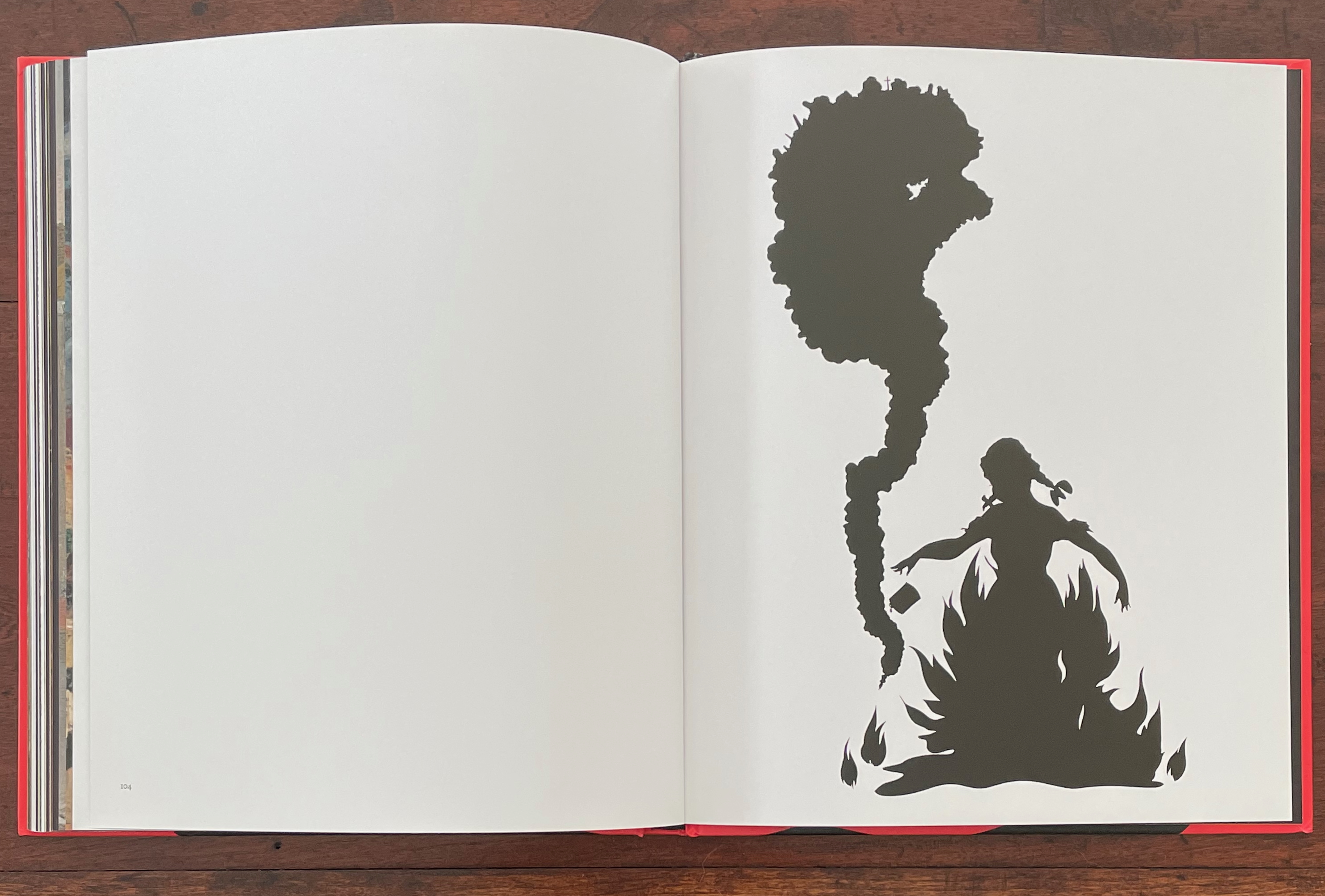 An open book page featuring a silhouette of a girl surrounded by flames and smoke, illustrating a dynamic scene.