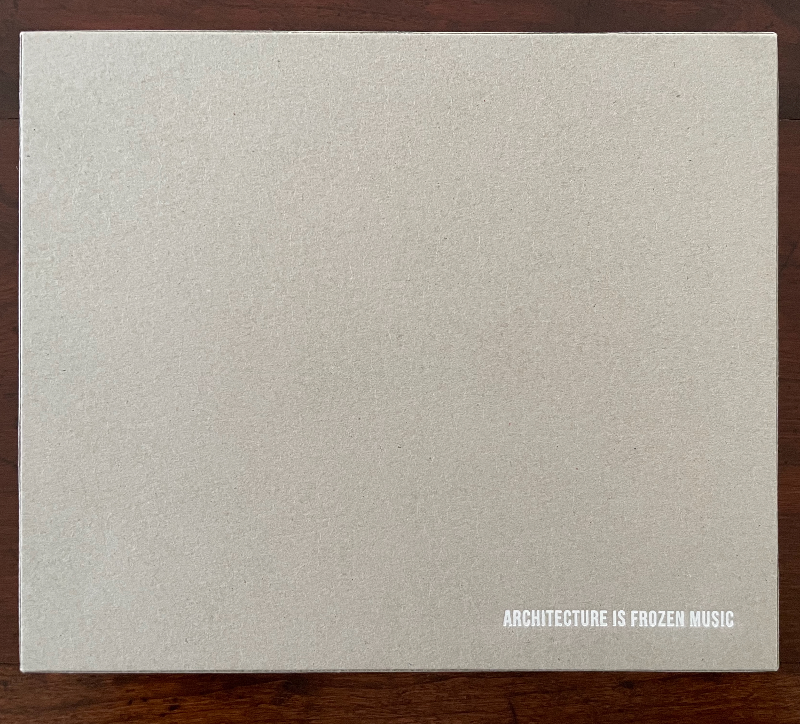 A textured, light gray book cover with the text 'ARCHITECTURE IS FROZEN MUSIC' written in white on the bottom right corner.