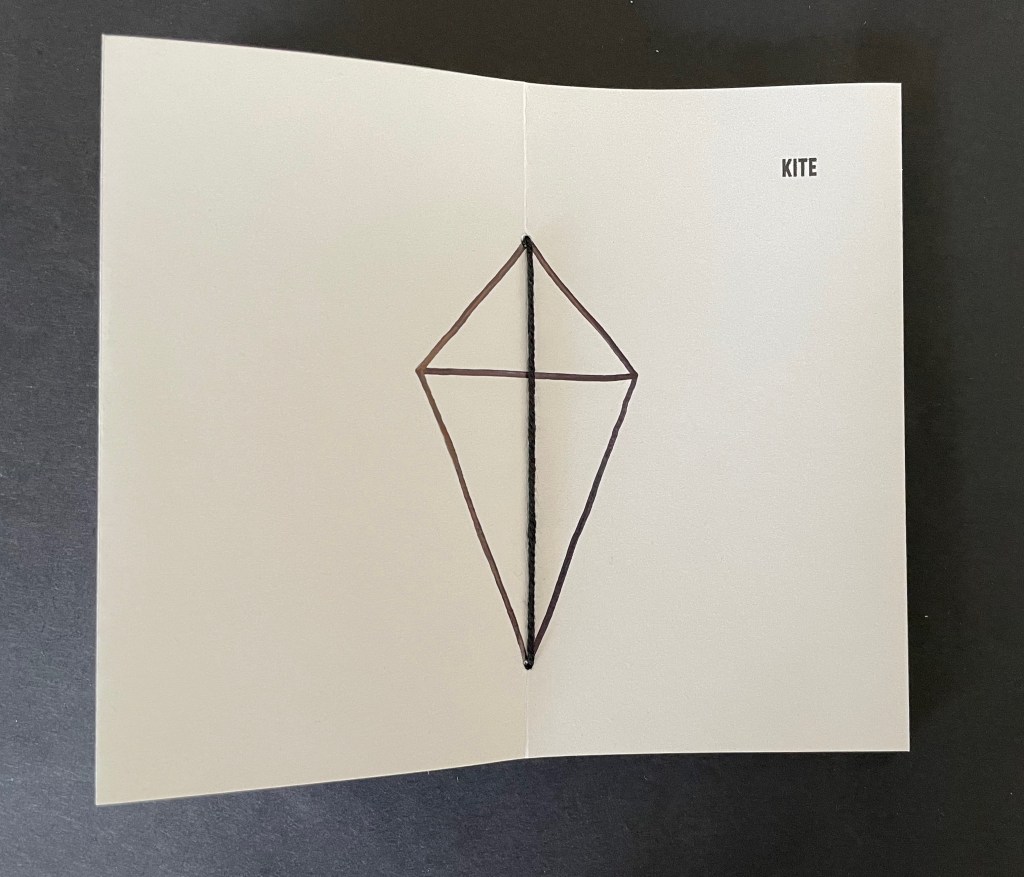 A simple drawing of a kite on an open card, with the word 'KITE' printed on the top right corner.