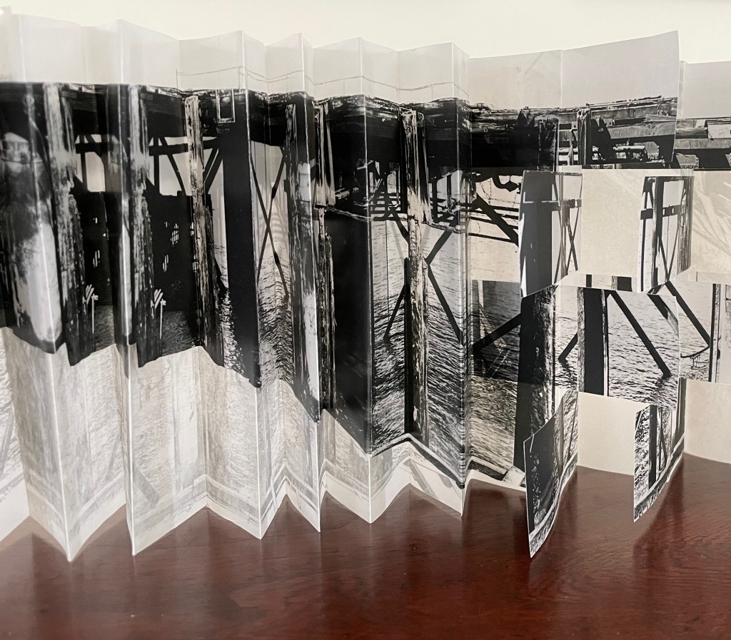 A folded photographic artwork featuring black and white images of a pier, showcasing structural details against a textured background.
