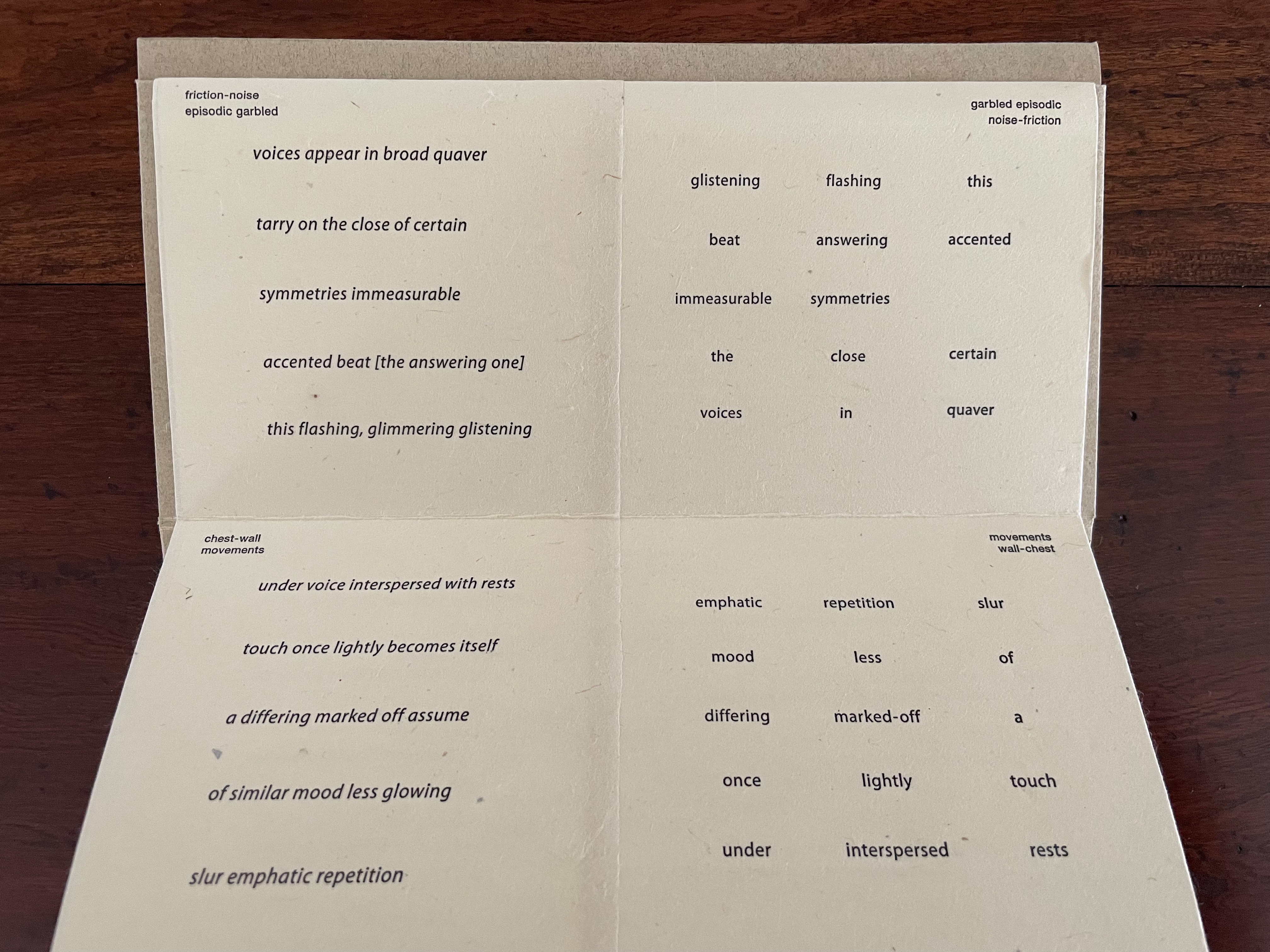 A folded paper containing poetic text, with phrases arranged in a visually interesting way, on a wooden surface.