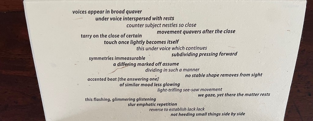 A close-up image of a poem or lyrical text displayed on a textured surface, featuring various lines of verse with a mix of poetic phrases and structure.