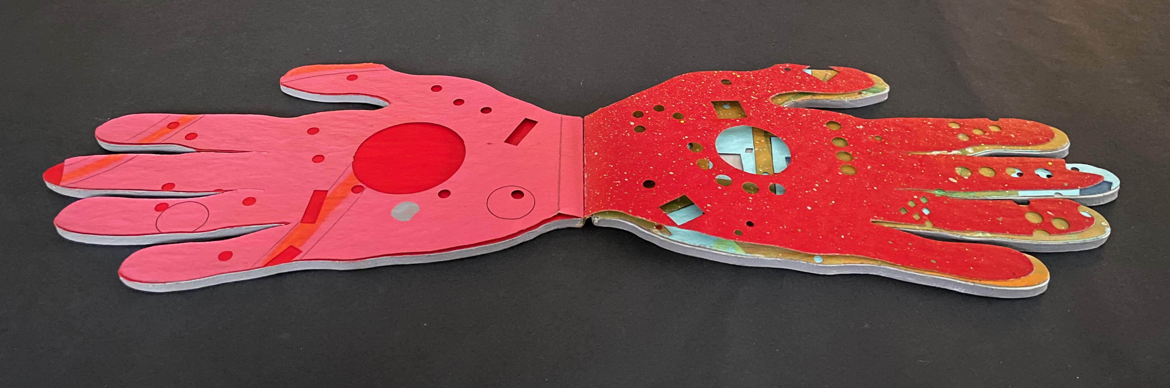 A colorful, abstract depiction of open hands in a layered design, featuring various shapes and cutouts against a black background.