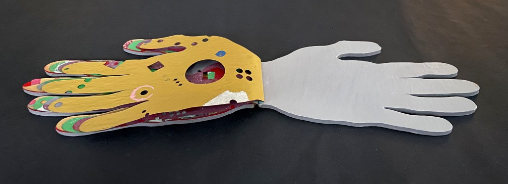 A two-sided artistic representation of a hand, with one side painted in bright colors and patterns, while the other side is a plain gray.