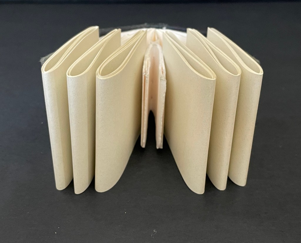 A closed, blank book with multiple pages, viewed from the side, resting on a dark background.