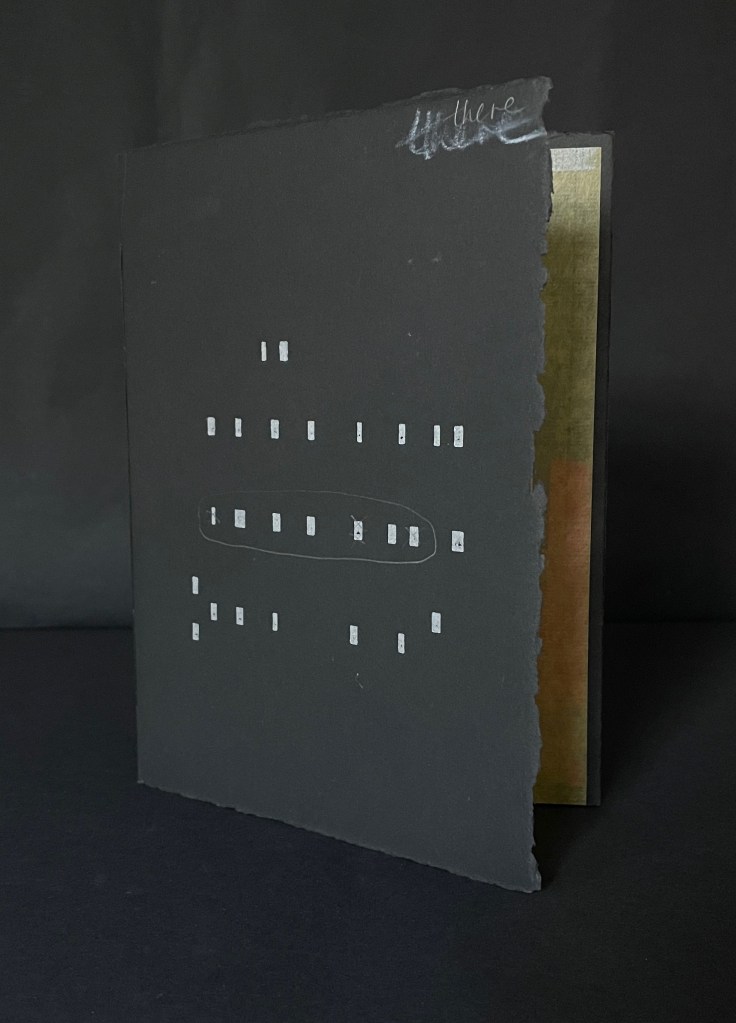 A black art book with textured pages and minimalist white markings on the cover, partially opened to reveal a golden inner page.