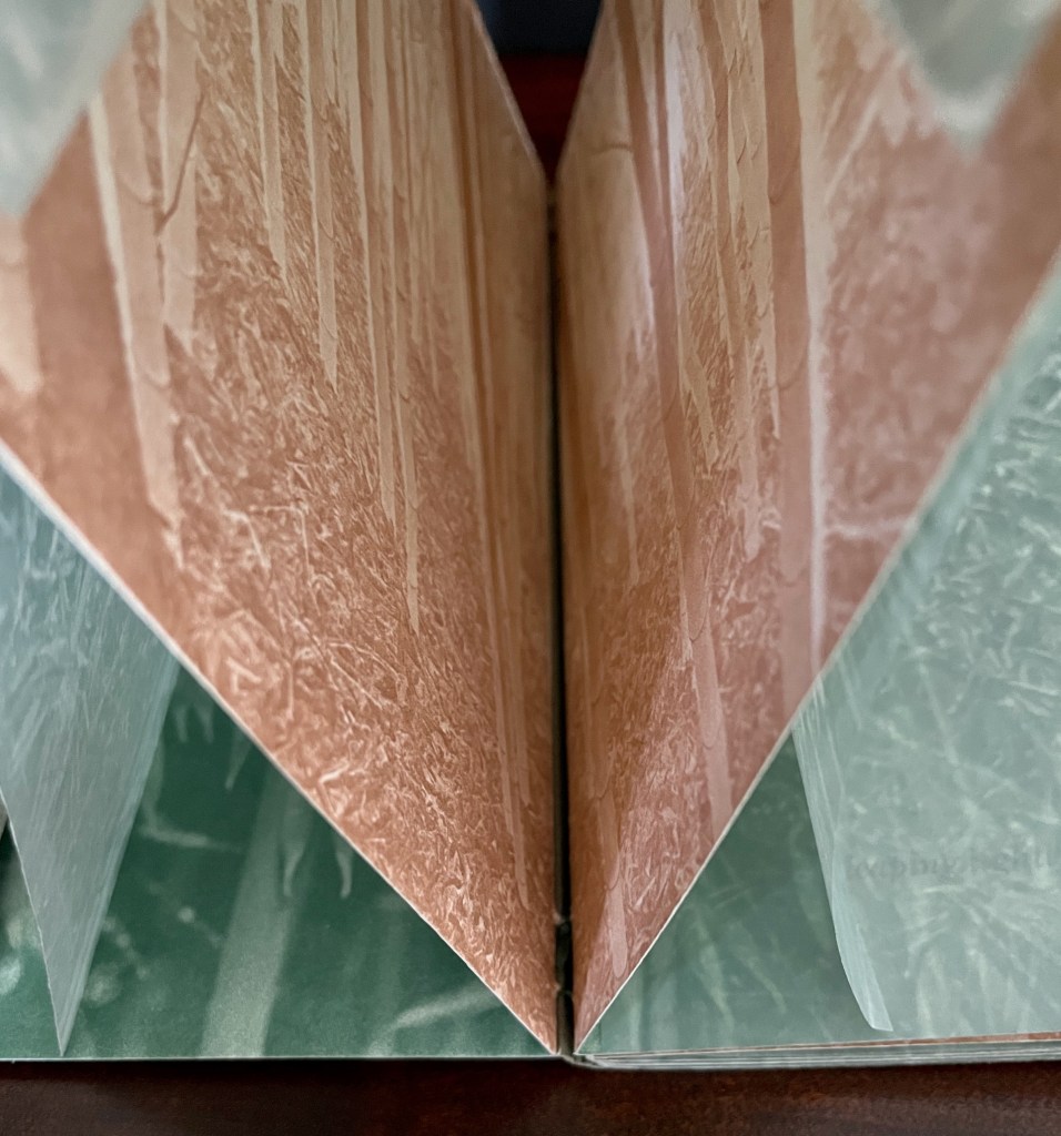 A close-up view of an open book displaying textured pages with a blend of earthy colors and natural imagery.