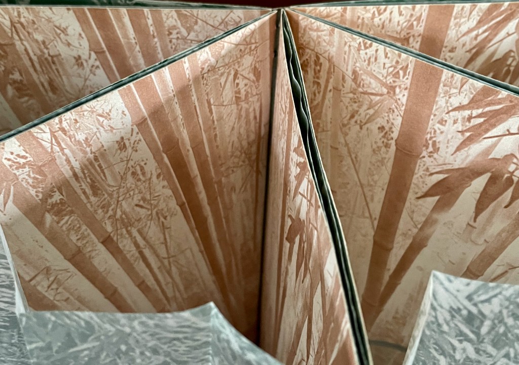 Close-up view of a folded book displaying intricate bamboo-themed artwork inside.