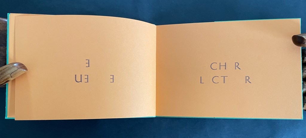 Open book with orange pages displaying text that reads 'E U' on the left page and 'C H R L C T R' on the right page.