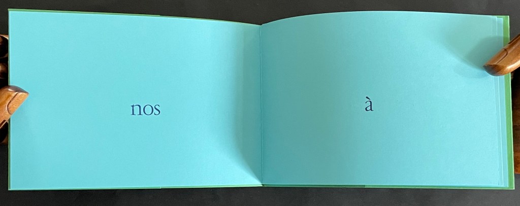 An open book with a turquoise background, displaying the words 'nos' on the left page and 'à' on the right page.