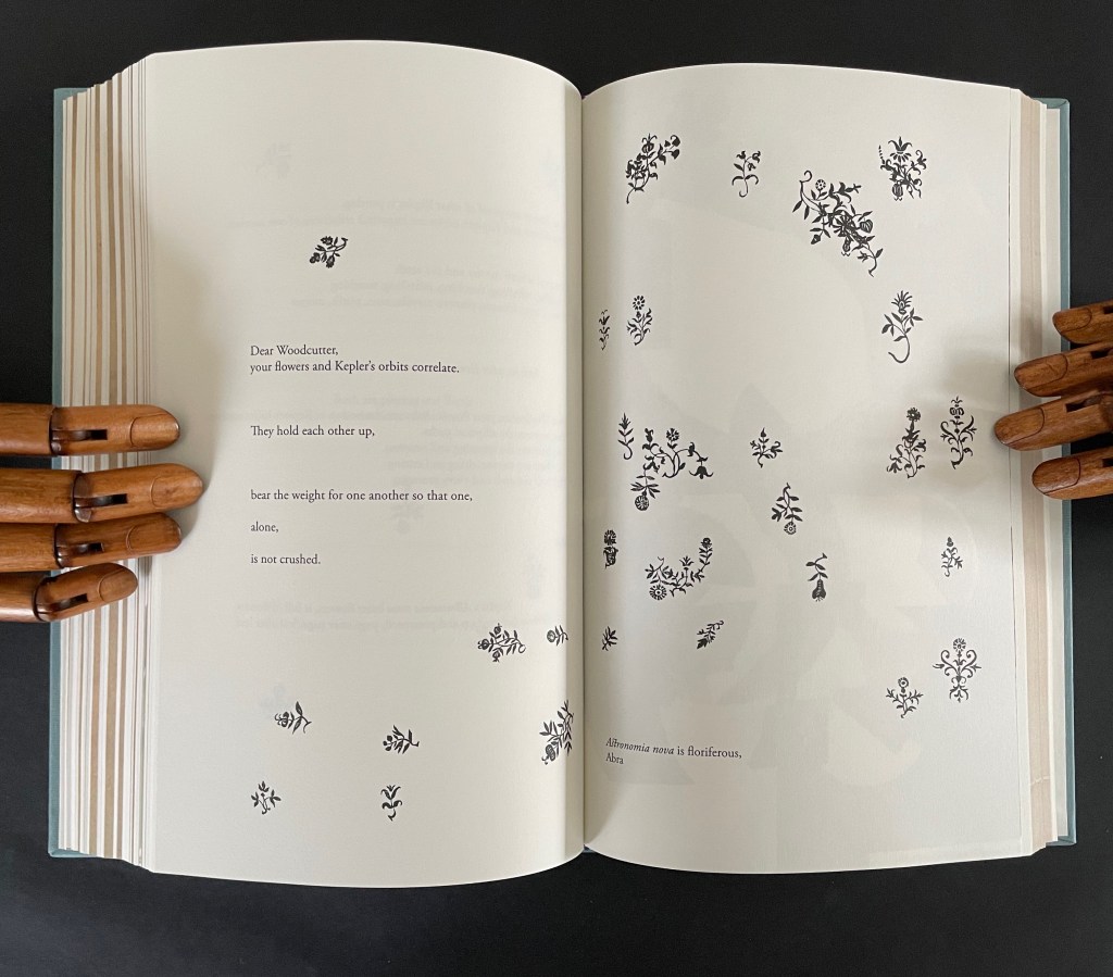 An open book displaying a page with handwritten text addressed to 'Woodcutter' and numerous botanical illustrations scattered across the page. The illustrations are in black ink, set against a simple white background, while wooden mannequin hands are holding the book.