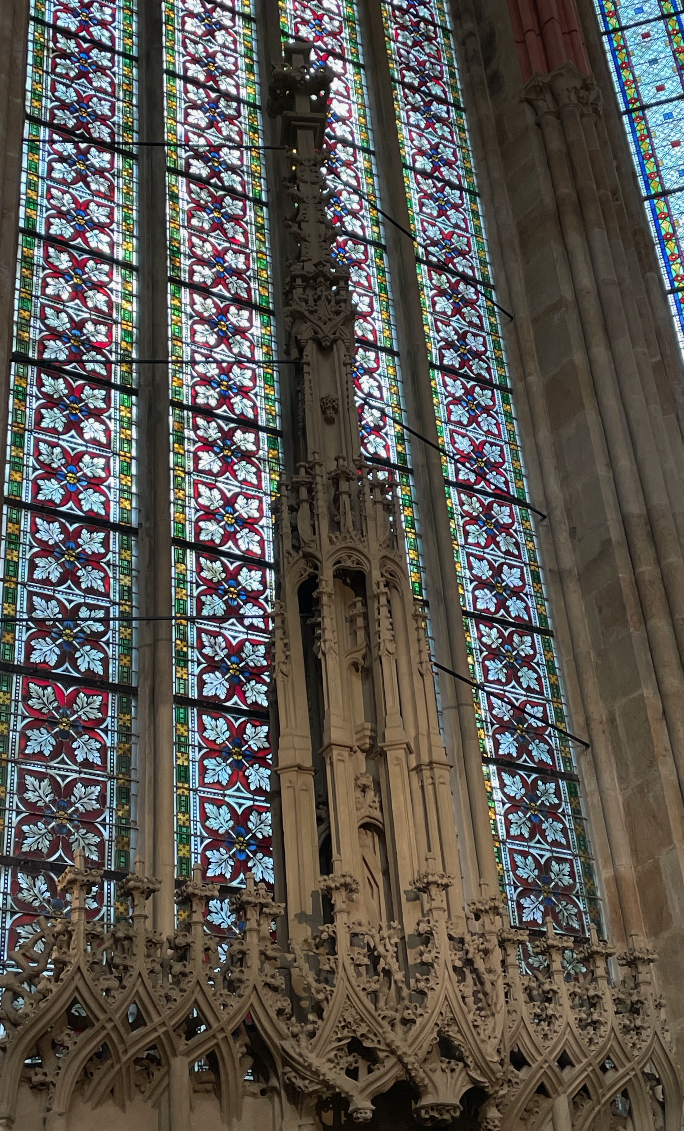 Intricate stonework displayed in front of colorful stained glass windows inside a cathedral.