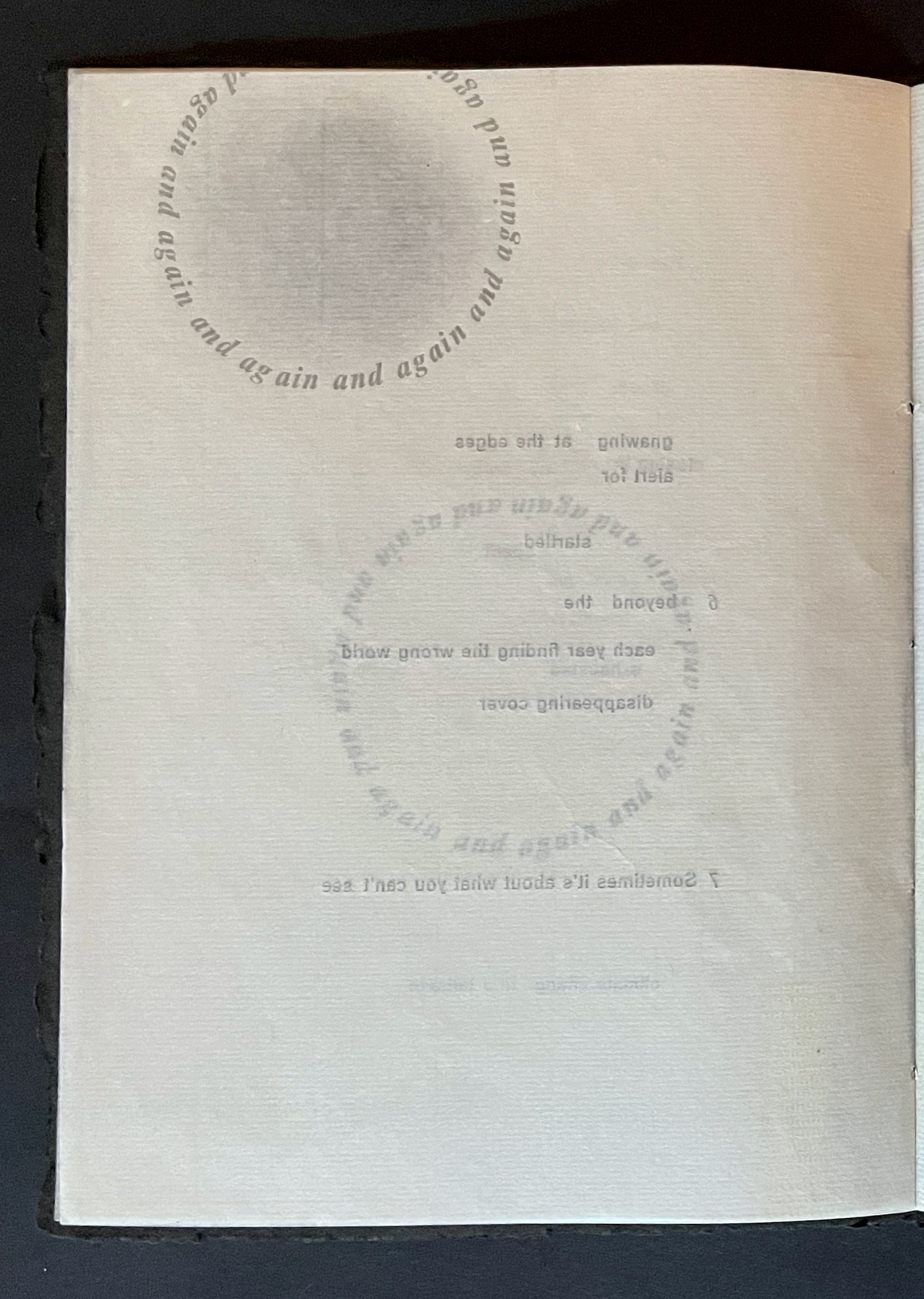A partially visible page from a book featuring faded text and circular text design, with phrases like 'again and again' and 'somebody's is about what you can't see.'