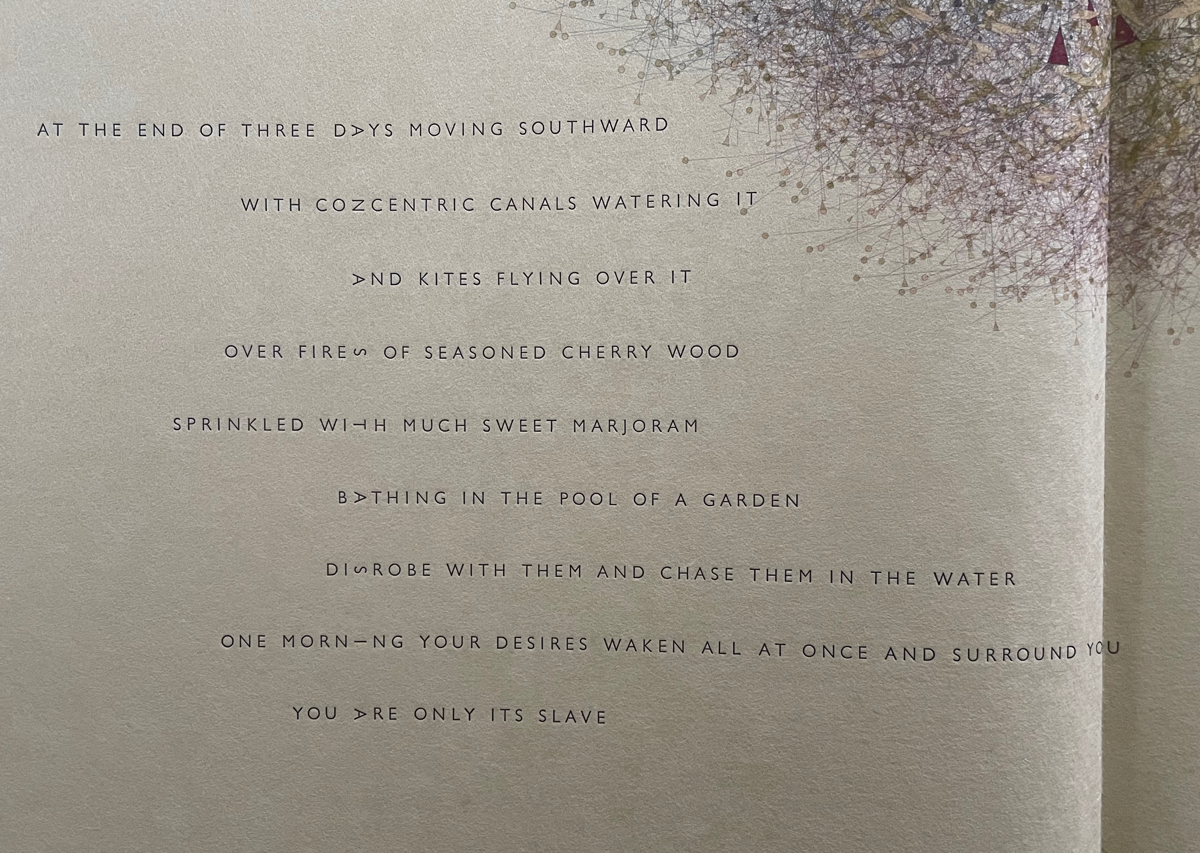 A close-up view of an open book page featuring poetic text with artistic design elements, including scattered geometric shapes and patterns in the background.