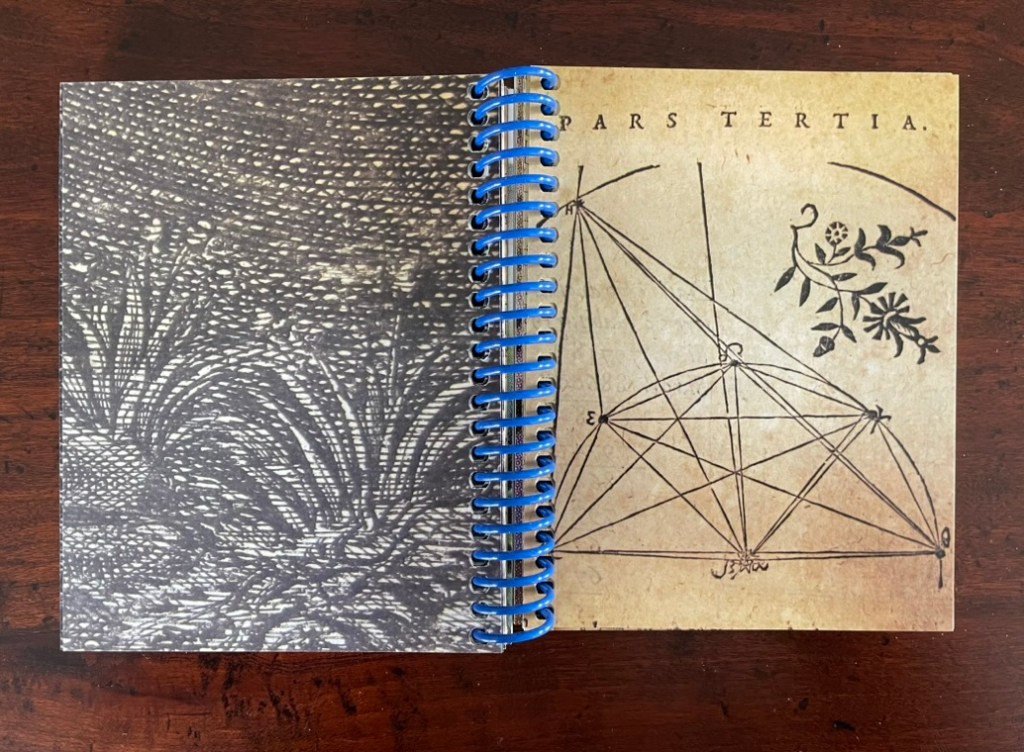 An open notebook with a patterned cover featuring a geometric illustration and handwritten notes, displayed on a wooden surface.