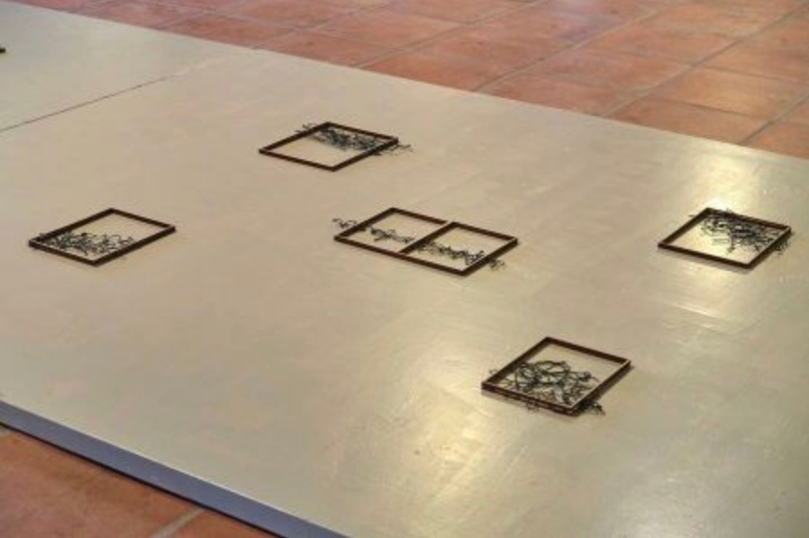A minimalist art installation featuring four empty, rectangular frames placed on a polished floor.