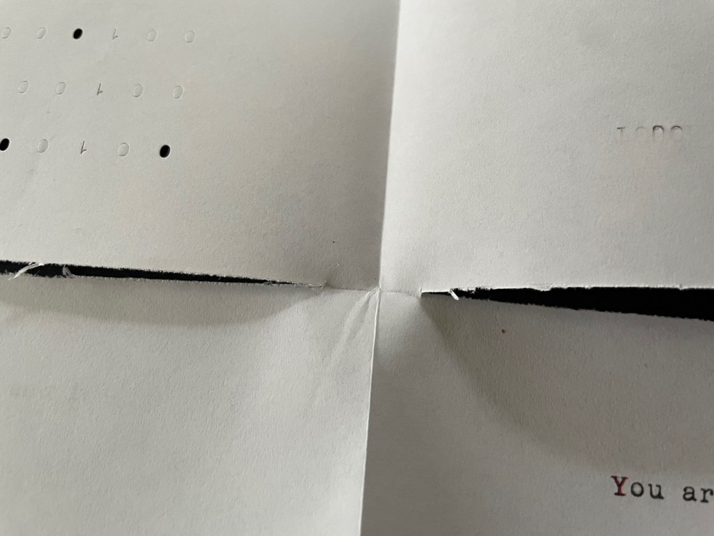 Close-up view of a folded piece of paper with embossed numbers and text that reads 'You are'.