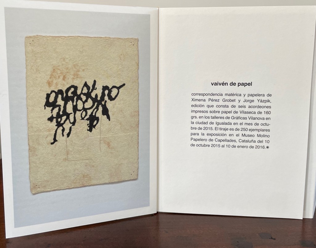 An artistic representation featuring black abstract shapes on textured paper, surrounded by a white border. The background includes printed text describing an art project titled 'vaivén de papel' by Ximena Pérez Grobet and Jorge Yáspik.