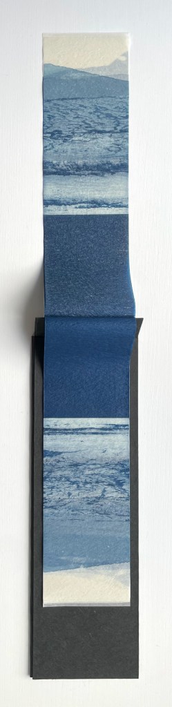 An artistic photograph featuring a vertical strip of blue-toned waves and ocean scenery, displayed against a black background.