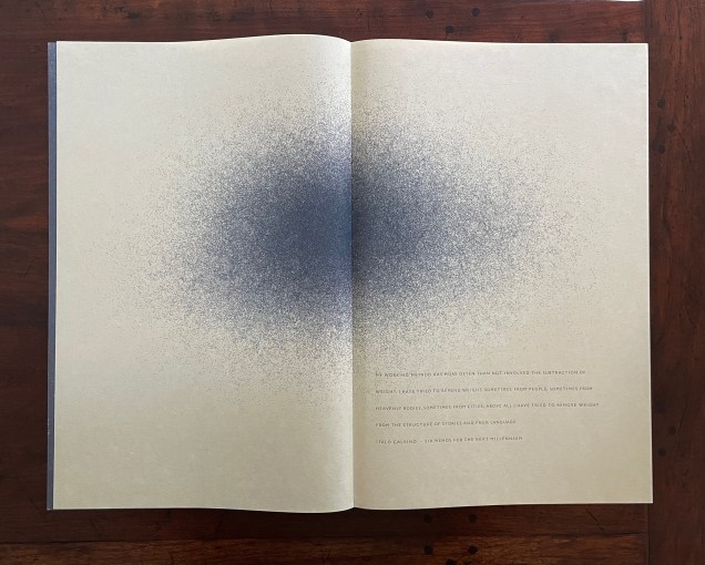 An open book on a wooden surface featuring pages with a gradient dot pattern transitioning from dark to light, accompanied by text on the right page.