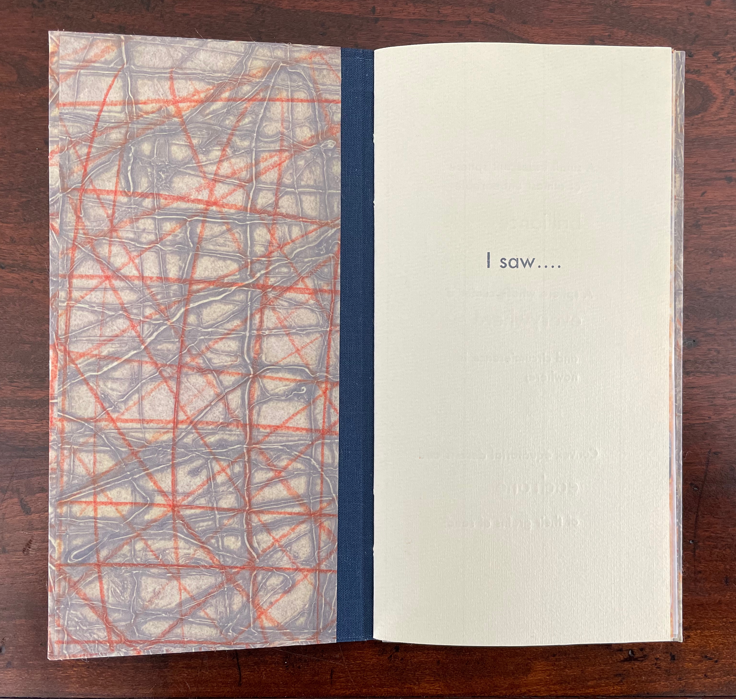 An open book displaying a textured page with orange and gray lines on one side and a blank page with the text 'I saw....' on the other.