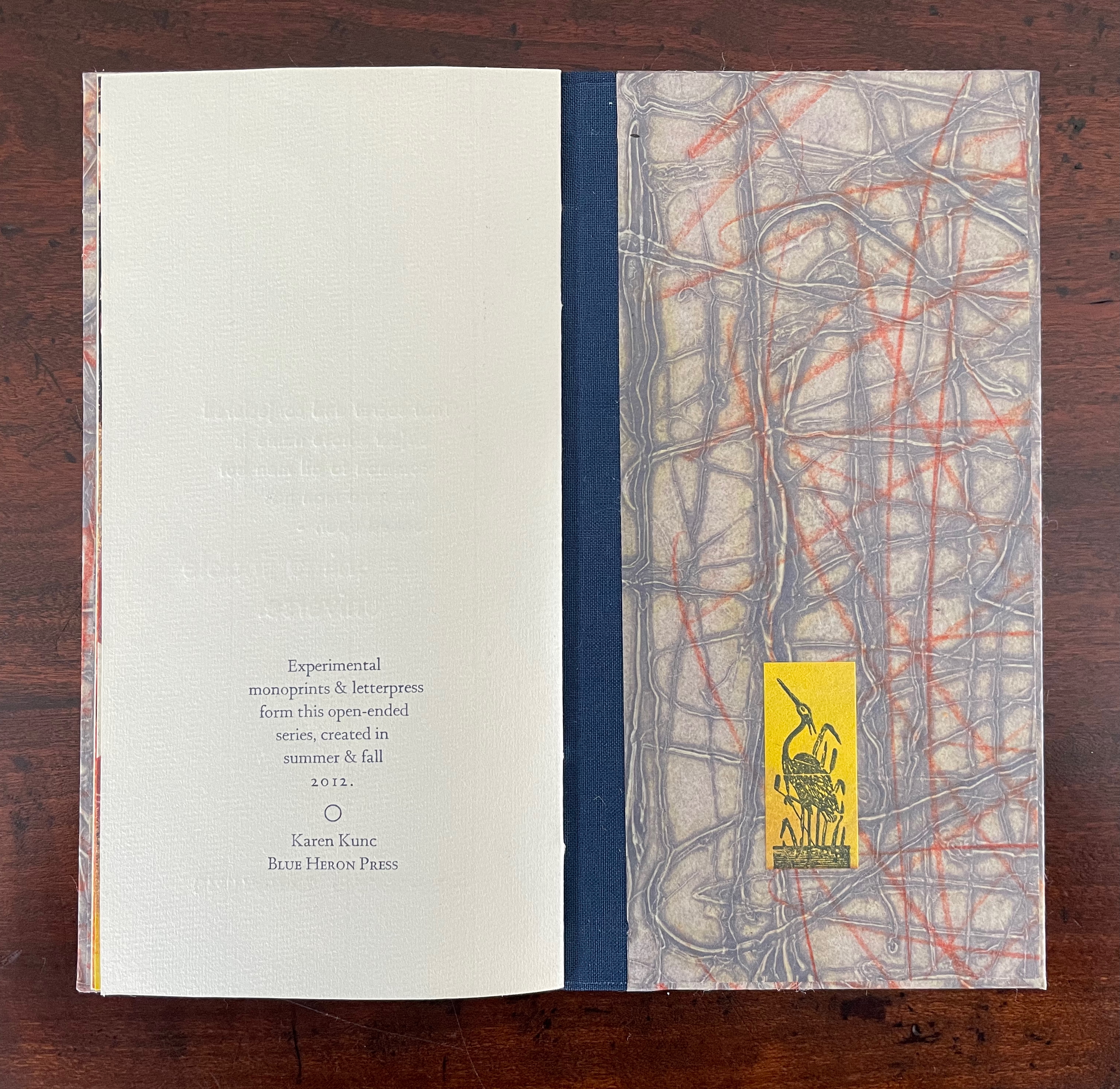 Open book displaying textured artwork on the cover, featuring abstract patterns in gray, orange, and yellow, along with text detailing the author's name and publication information.