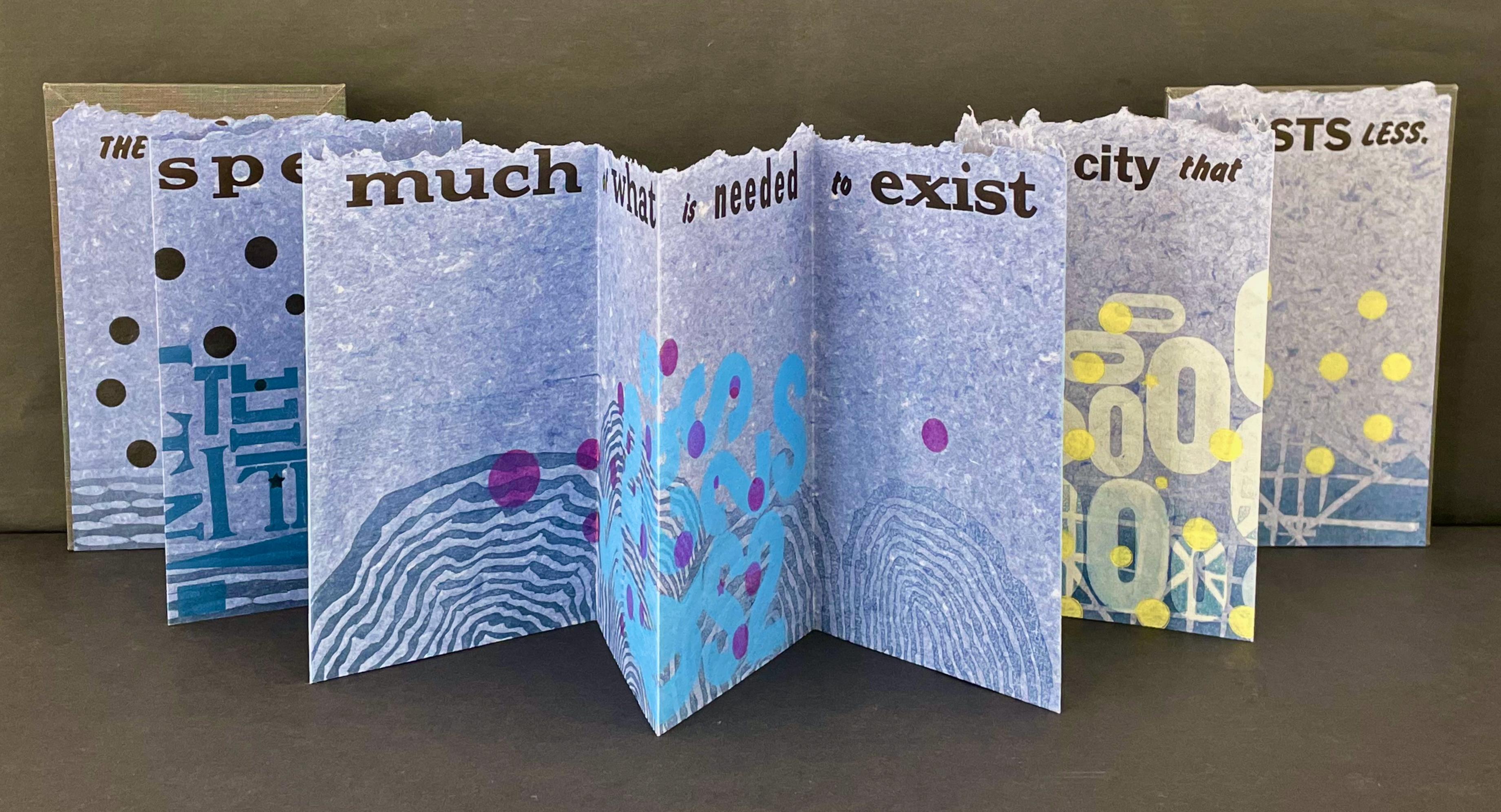 A folded artist book with abstract designs and text on blue textured pages, featuring phrases about existence and cities.