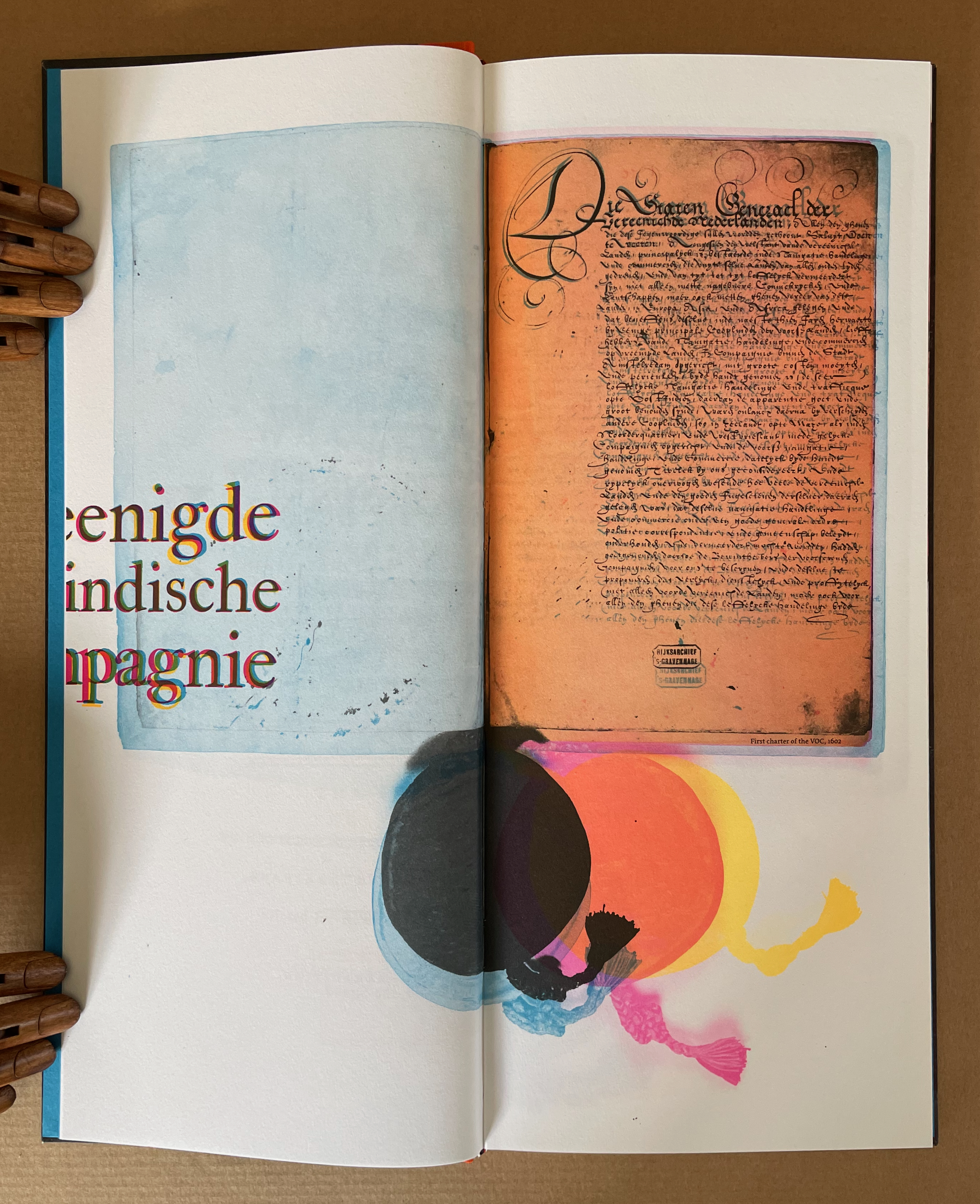 An open book with colorful abstract designs, showing a historical document on the right page and an empty blue page on the left, featuring the text 'Eenige Indische Compagnie.'