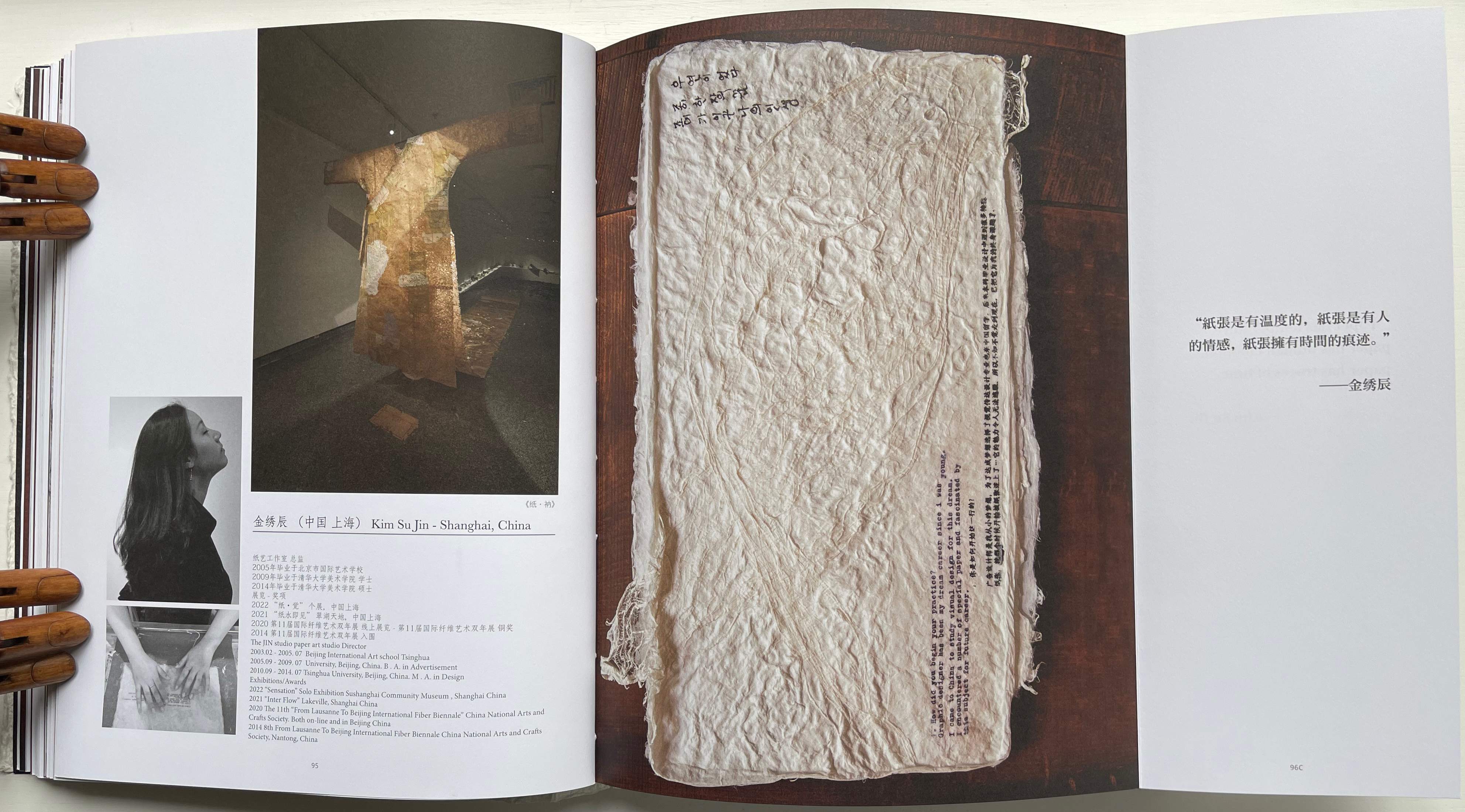 A page from an art book featuring an image of a large textured piece resembling traditional clothing made of paper, alongside a portrait of a woman gazing upwards. Text about the artist Kim Su Jin and her work is included.