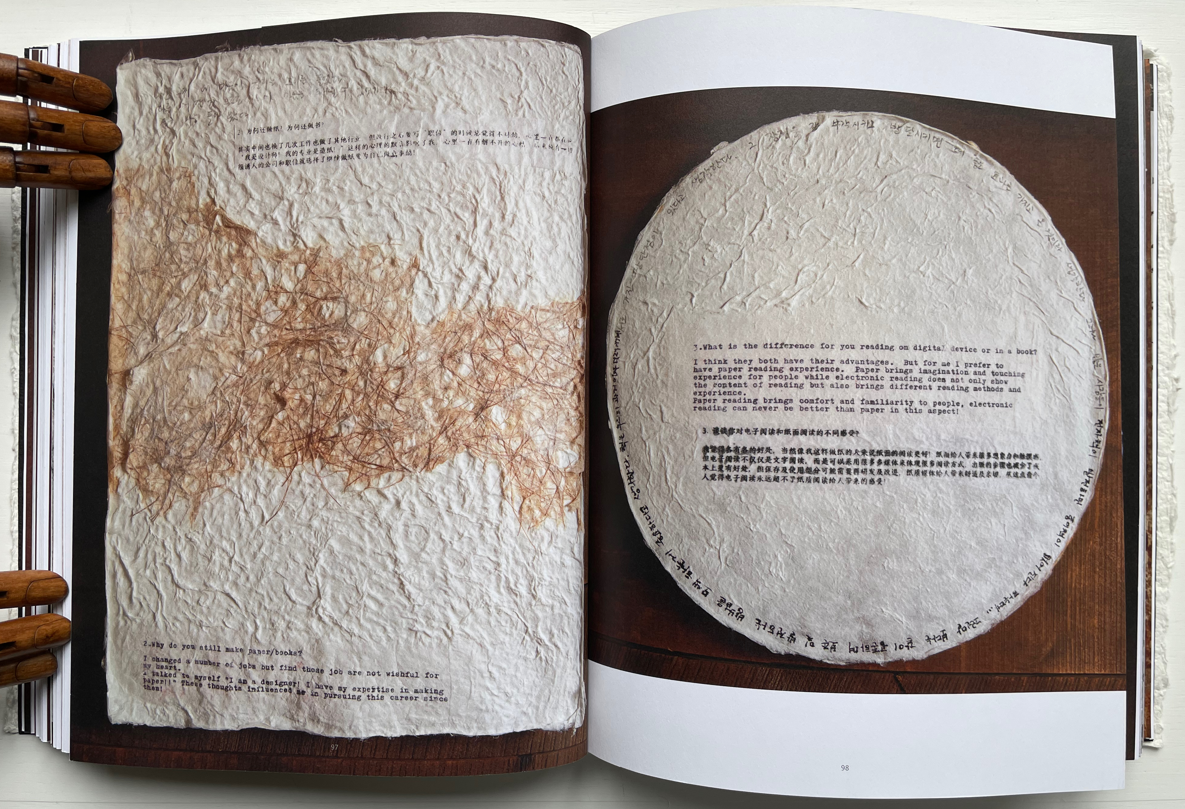 Open book spread featuring a textured page with a brownish pattern on the left and a circular page with printed text in black and white on the right, surrounded by wood.