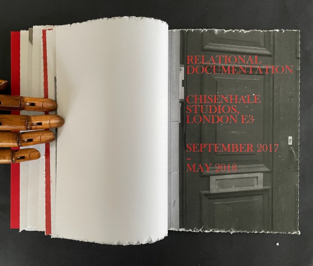 Open book displaying the title 'Relational Documentation', with details of Chisenhale Studios in London and a date range from September 2017 to May 2018, alongside a wooden hand holding the pages.